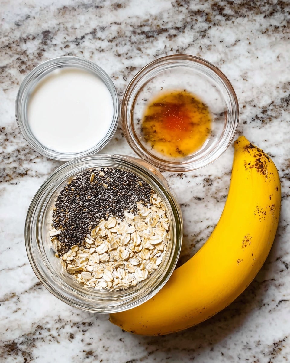 The image shows ingredients for a dish placed on a white marbled surface. There is a large transparent glass jar in the center containing three layers from bottom to top: small black chia seeds, tan rolled oats, and a small amount of amber-colored liquid on one side. To the left, there are two small glass bowls stacked with one containing white foamy liquid and the other filled with white creamy substance. On the right side of the jar, there is a whole yellow banana with some small brown spots. photo taken with an iphone --ar 4:5 --v 7