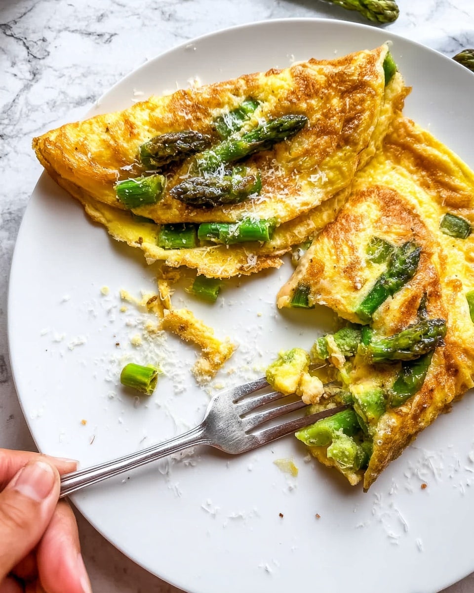 A white plate with two folded golden-brown omelets filled and topped with green asparagus pieces, showing texture from the cooked eggs and the bright green of the asparagus. One omelet has a corner torn off, revealing the soft yellow inside mixed with chunks of asparagus. There are white flaky bits sprinkled on top and around the plate. A metal fork with some egg and asparagus is on the plate, and a woman's hand is holding the fork. The background is a white marbled surface. photo taken with an iphone --ar 4:5 --v 7