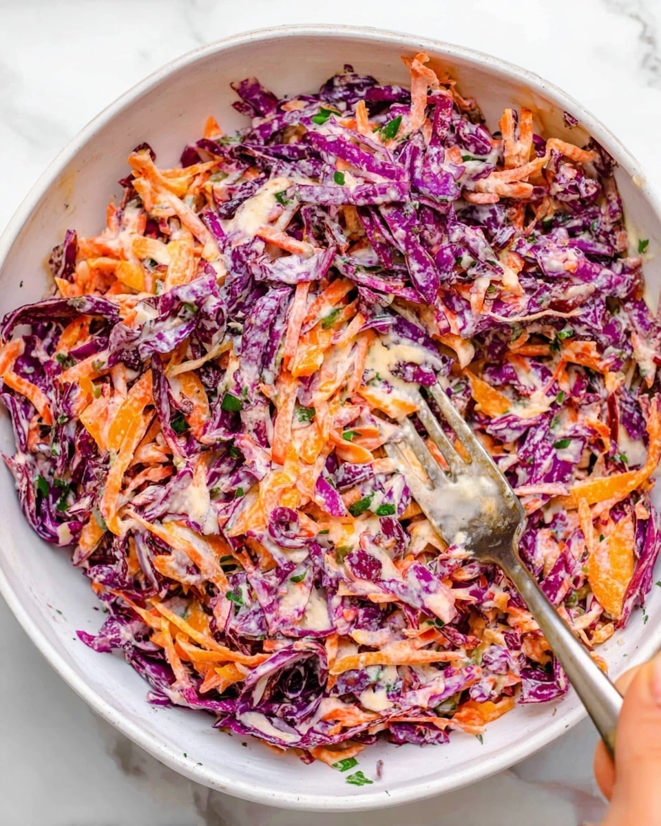 A white bowl filled with a colorful salad made of shredded purple cabbage and grated orange carrots mixed together with a creamy dressing, small green herb bits scattered throughout. A woman's hand holds a silver fork dipping into the salad at the bottom right corner. The bowl sits on a white marbled surface. photo taken with an iphone --ar 4:5 --v 7