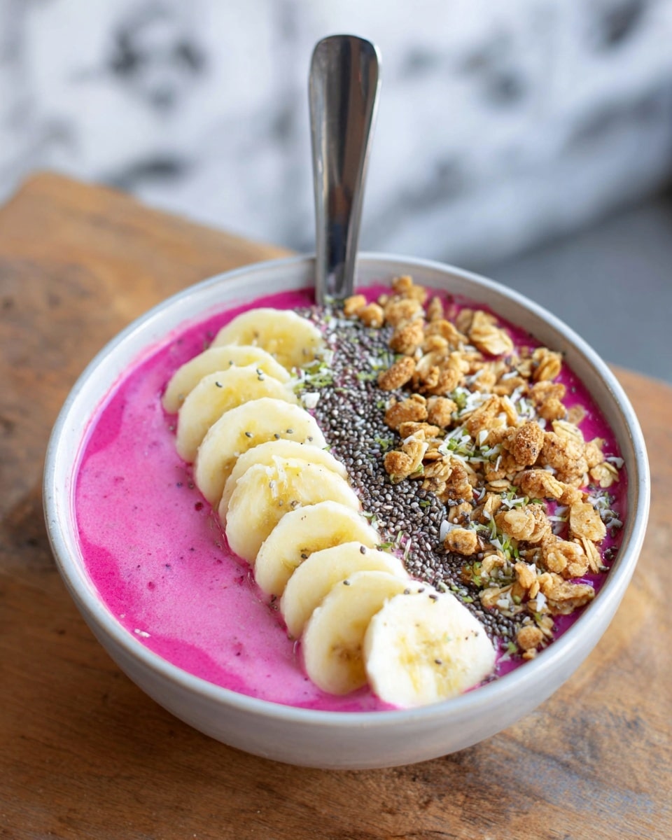 A white bowl filled with bright pink smoothie as the base layer, topped with a neat row of banana slices on one side, light yellow with creamy texture. Next to the bananas is a layer of crunchy, light brown granola clusters. Scattered over the bananas are small black chia seeds adding texture. A silver spoon is placed inside the bowl, standing vertically. The bowl is set on a wooden surface with a blurred white marbled textured background. Photo taken with an iphone --ar 4:5 --v 7