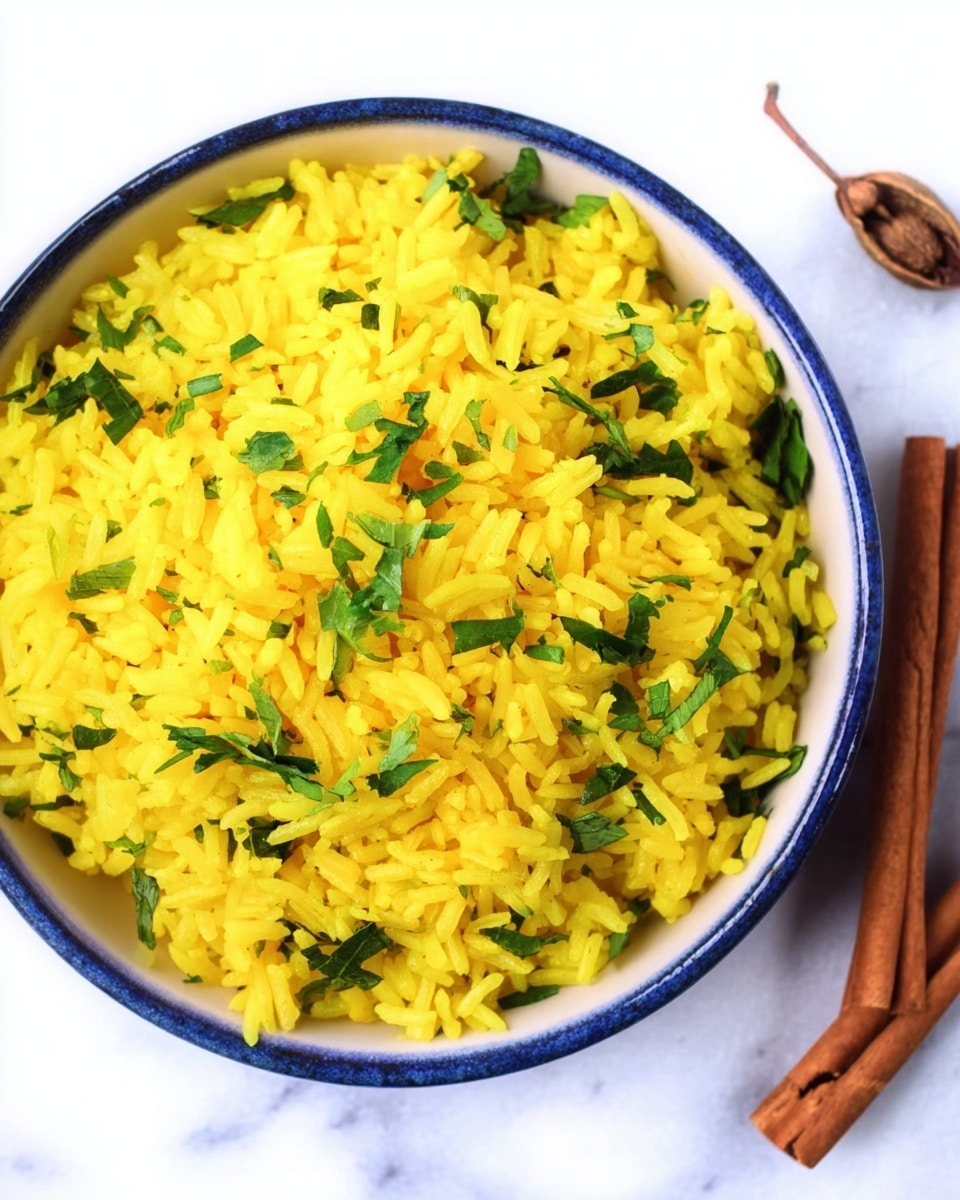 A bowl filled with yellow rice mixed with small chopped green herbs on top. The bowl is white with a blue rim and the texture of the rice looks fluffy and soft. Next to the bowl on a white marbled surface are a cinnamon stick and a small clove. The photo is taken from above, showing the details of the rice grains and herbs clearly. photo taken with an iphone --ar 4:5 --v 7