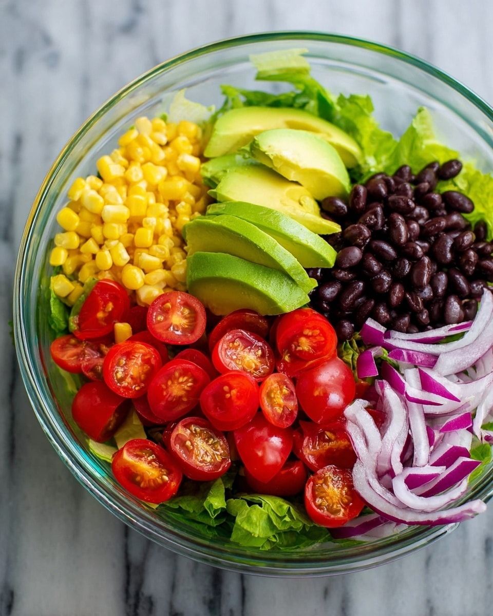 A clear bowl sits on a white marbled surface, filled with colorful salad ingredients arranged in separate sections. At the bottom is a base layer of green lettuce leaves. On top of the lettuce, starting from the left, is a mound of yellow corn kernels, followed by neatly sliced avocado with a smooth, green texture. Next to the avocado are dark, shiny black beans in a neat pile. To the right of the beans are thin, light purple slices of red onion, and in the front is a group of bright red, halved cherry tomatoes showing their juicy interiors. The ingredients are fresh and vibrant, visibly separated in the bowl. Photo taken with an iphone --ar 4:5 --v 7