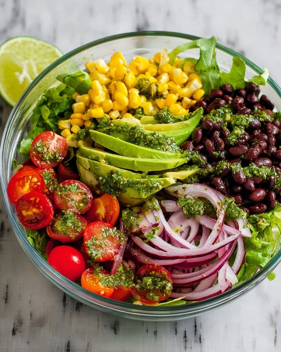 A clear glass bowl is filled with layers of fresh salad ingredients on a white marbled surface. The bottom layer is green leafy lettuce. On top, there are bright yellow corn kernels on the left side, a fan of sliced avocado with a green herb dressing in the center, and a section of black beans on the right. Below the avocado and beans, thin slices of red onion with the same herb dressing are placed. On the left front side, there are halved red cherry tomatoes covered with herb dressing. A wedge of lime is placed near the avocado. photo taken with an iphone --ar 4:5 --v 7