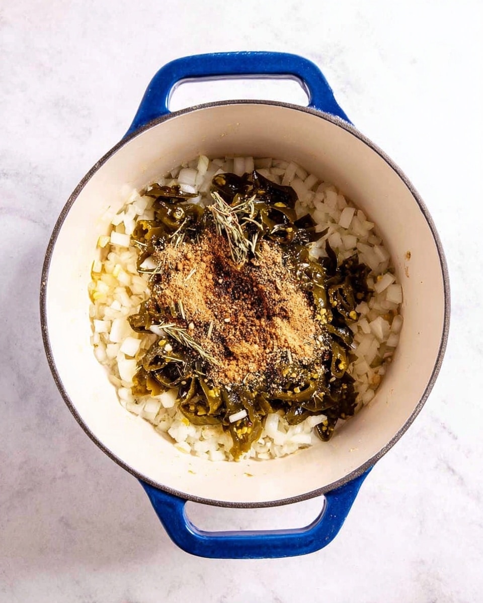 A white pot with blue handles is shown from above, placed on a white marbled surface. Inside the pot, the base layer consists of small chopped white onions spread evenly. On top of the onions, there are roughly chopped dark green pickled jalapeños scattered mainly in the center. Over the jalapeños, there is a layer of light brown ground spices sprinkled unevenly, including some dried herbs. The colors are soft white, dark green, and light brown, with a clear separation between each layer photo taken with an iphone --ar 4:5 --v 7