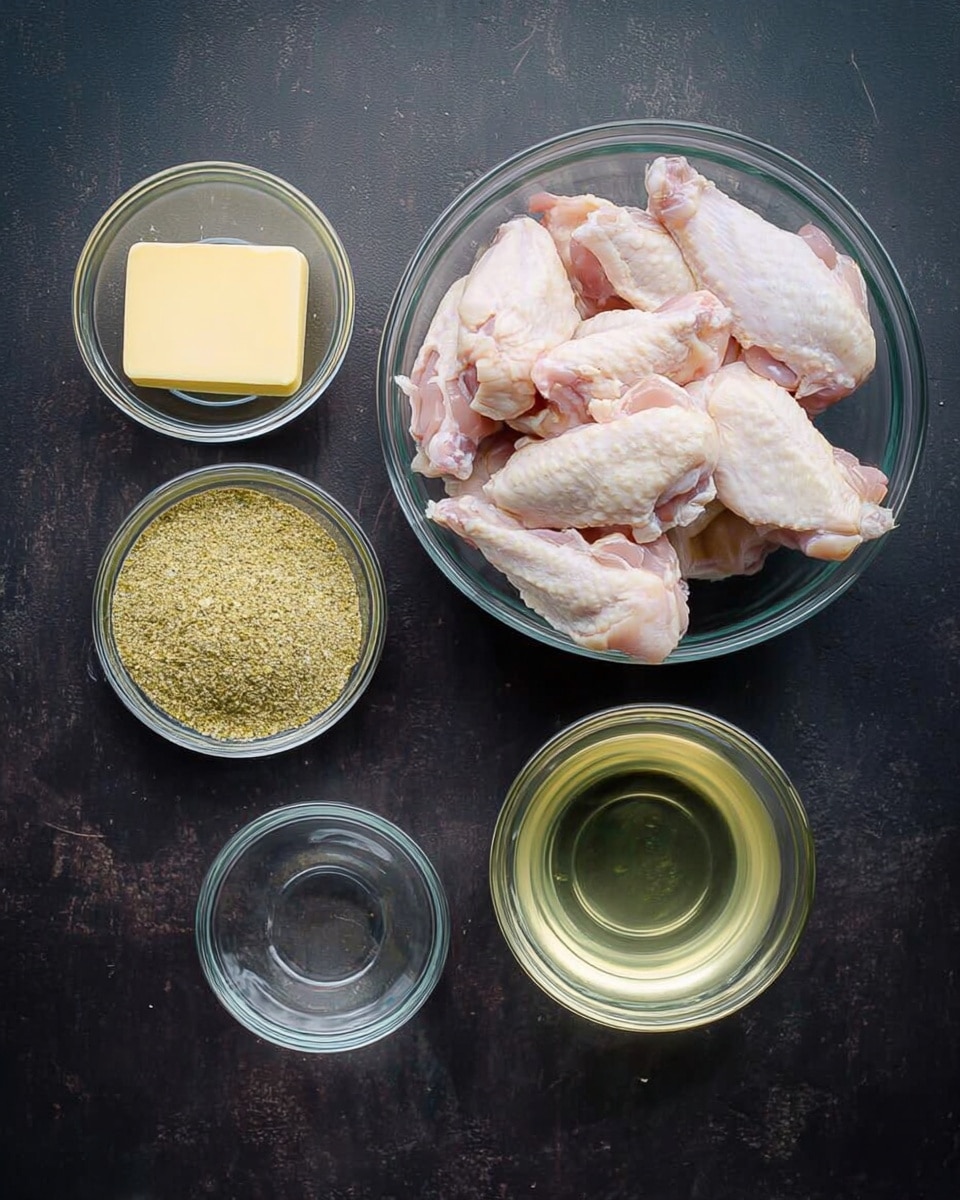 The image shows a clear glass bowl filled with raw chicken wings in the top right. Below it, there is a small clear glass bowl with a pale yellow liquid. To the left of that bowl, there is another small clear glass bowl filled with greenish-yellow seasoning powder. Above both these bowls, on the top left, there is a small clear glass bowl with a rectangular piece of yellow butter. The bowls are placed on a dark surface with a slightly rough texture. photo taken with an iphone --ar 4:5 --v 7