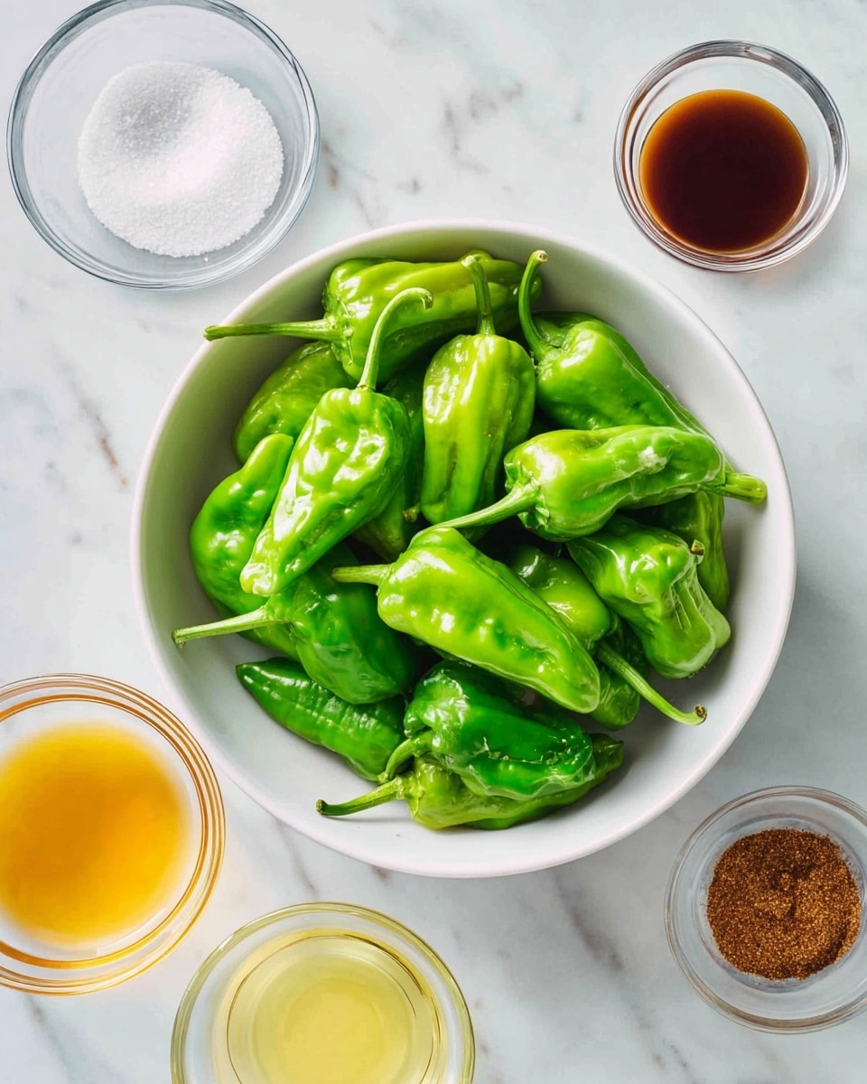 A large white bowl filled with many fresh, shiny green peppers, each with smooth, slightly crinkled skin and attached stems, sits on a white marbled surface. Surrounding the bowl are four small clear glass bowls arranged around it: the top left bowl holds white coarse salt, the top right bowl contains a dark brown sauce with a glossy finish, the bottom left bowl has a yellowish liquid, and the bottom right bowl shows a brown spice powder. The overall look is clean and bright with a fresh feel, photo taken with an iphone --ar 4:5 --v 7