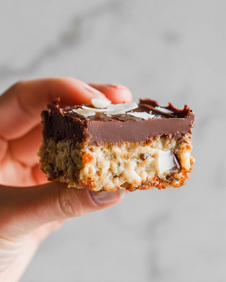 A close-up of a two-layered square snack held by a woman's hand. The bottom layer is thick and filled with small bits of orange, white, and light brown pieces, with a soft and dense texture. The top layer is a smooth, thick dark brown chocolate spread evenly over the bottom layer, with a few light-colored flakes sprinkled on top. The background is a white marbled texture. photo taken with an iphone --ar 4:5 --v 7