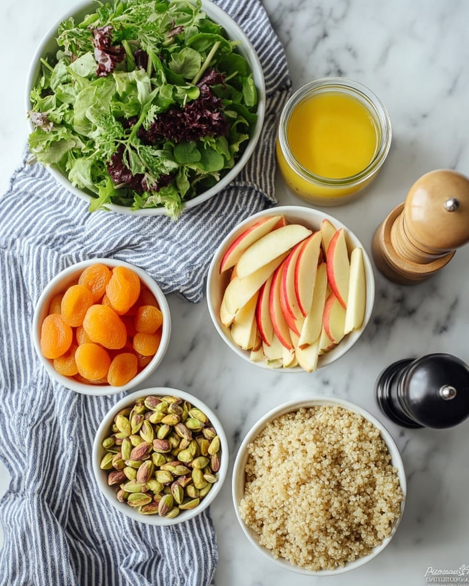 The image shows six white bowls and a jar arranged on a white marbled surface with a blue and white striped cloth underneath. The top left bowl is filled with fresh mixed green leafy vegetables with different shapes and shades of green. To its right is a small glass jar of yellow dressing. Below the jar is a white bowl with thin, pale yellow and red apple slices. Below and left of that is a bowl filled with green and beige pistachio nuts. To the left of the pistachios is a bowl full of dried bright orange apricots. The bottom center bowl contains fluffy beige cooked quinoa. To the right of the bottom bowl is a black pepper grinder. The scene is bright with soft natural light. Photo taken with an iphone --ar 4:5 --v 7