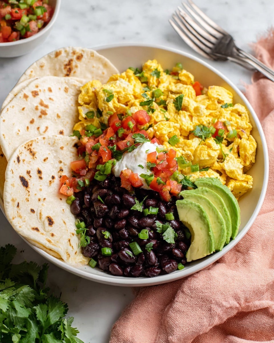A white bowl holds a colorful dish with four main layers arranged side by side. On one side, there are four folded white tortillas with light brown spots stacked neatly. Next to them, a soft, yellow scrambled egg mix with bits of green herbs and red tomatoes is piled up. In the corner beside the eggs, there are dark black beans with a small dollop of white sour cream topped with chopped green onions. On the edge of the bowl, three slices of green avocado peek out behind the beans. A small amount of fresh green cilantro leaves and red tomato salsa sit on top of the eggs, adding bright colors. Everything rests on a white marbled surface with a soft pink cloth and forks blurred in the background. photo taken with an iphone --ar 4:5 --v 7