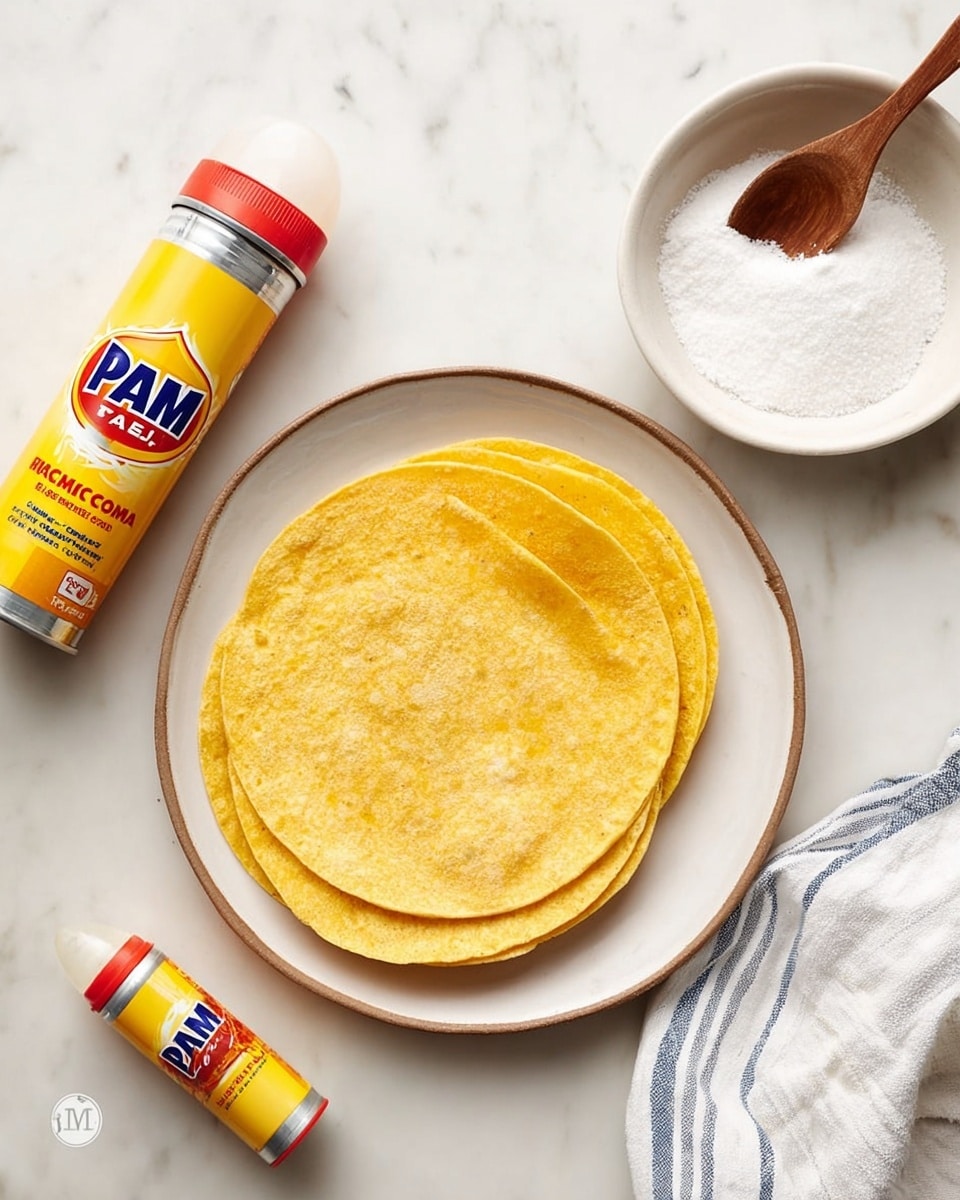 The image shows a stack of yellow corn tortillas placed in the middle of a white plate with a slight brown rim, sitting on a white marbled surface. To the top right of the plate is a small white bowl filled with coarse salt, and a small wooden spoon rests on the bowl. Below the salt bowl and next to the plate is a yellow and red spray can of PAM Original cooking spray laying on its side. A white and blue striped cloth is partially seen on the right edge of the image. Photo taken with an iphone --ar 4:5 --v 7