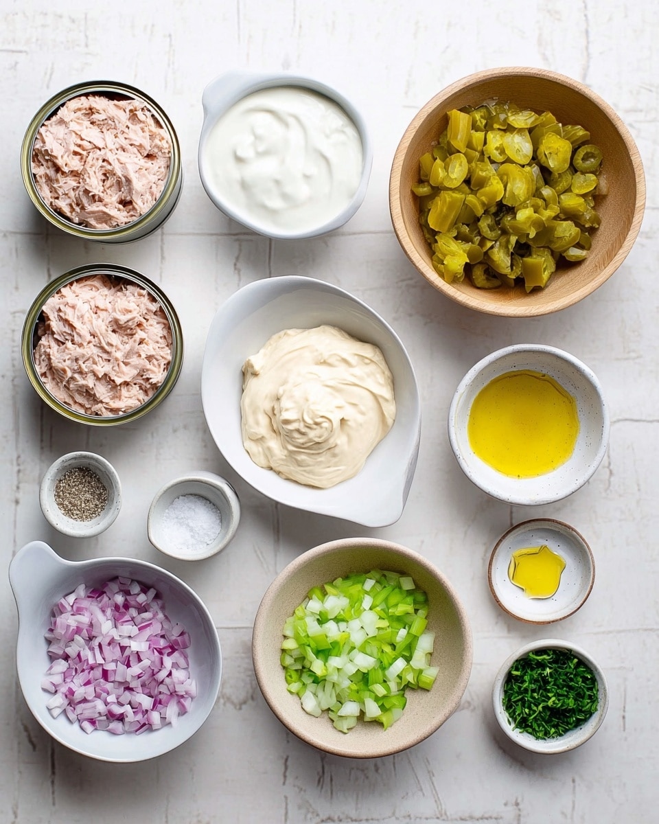 The image shows an assortment of ingredients neatly arranged on a white marbled surface, with two open cans of light pink tuna at the left side. There is a white bowl in the center filled with creamy mayonnaise, next to it a small white cup contains thick white yogurt. Above these is a small wooden bowl with finely chopped red onions and close by a similar bowl holds links of chopped pickles, yellow-green in color. A white measuring cup holds diced celery, and a brown bowl nearby contains finely chopped green herbs. To the right, three small white dishes hold a yellow mustard dollop, clear light yellow oil, and salt mixed with pepper. The image is bright, clean, and organized, photo taken with an iphone --ar 4:5 --v 7