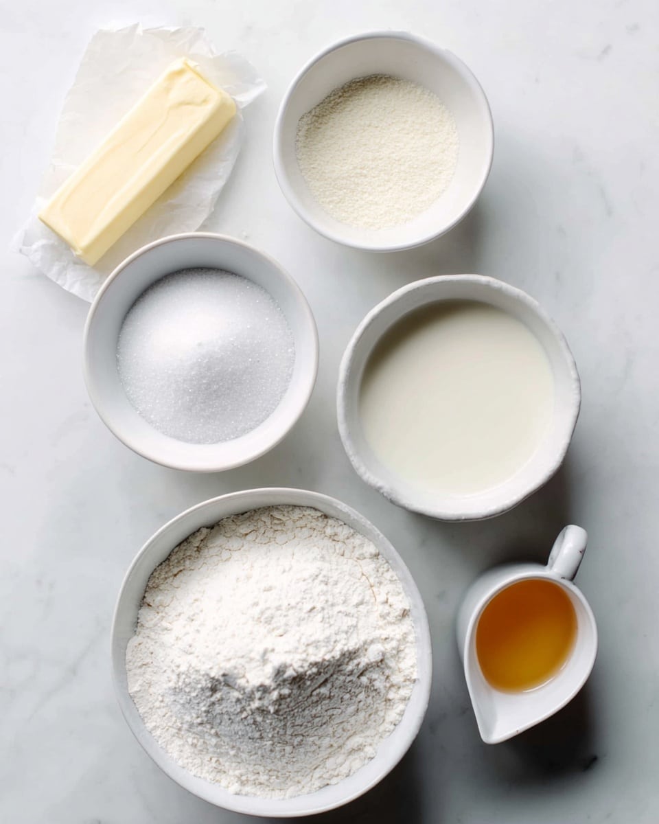 The image shows five white bowls and a stick of butter on a white marbled surface. The largest bowl at the bottom contains white flour with a soft, powdery texture. To its left, a medium white bowl holds granulated white sugar, looking fine and crystalline. Next to it is a small rectangular stick of pale yellow butter wrapped in paper. Above the sugar bowl is a small round white bowl with a grainy white substance. To the right, a medium white bowl is filled with a creamy white liquid, smooth and glossy. At the far right, a small white spouted bowl contains a light amber liquid with a clear texture. The items are arranged neatly with space between them. Photo taken with an iphone --ar 4:5 --v 7