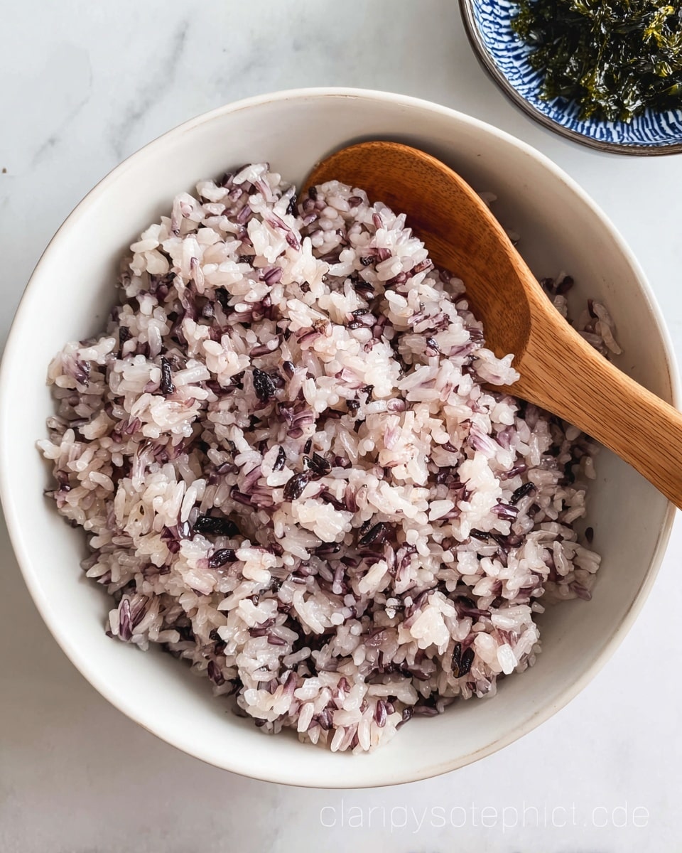 A white bowl filled with cooked rice that has a light purple color mixed with some darker purple grains, giving it a speckled look. On the right side inside the bowl, there is a wooden spoon resting on the rice. The bowl is placed on a white marbled surface. photo taken with an iphone --ar 4:5 --v 7