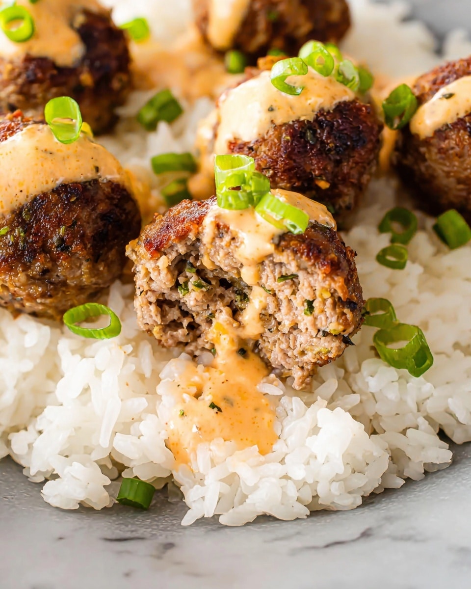 The image shows a close-up of several small meatballs placed on a bed of white rice. The meatballs have a browned, crispy outer layer with a textured, slightly crumbly inside that shows bits of green herbs. Each meatball is topped with a light orange, creamy sauce that drips slightly down the sides, and small pieces of green onion are scattered on top and around the meatballs. The dish sits on a smooth white marbled surface, highlighting the contrasting colors and textures of the rice, meatballs, and sauce. photo taken with an iphone --ar 4:5 --v 7