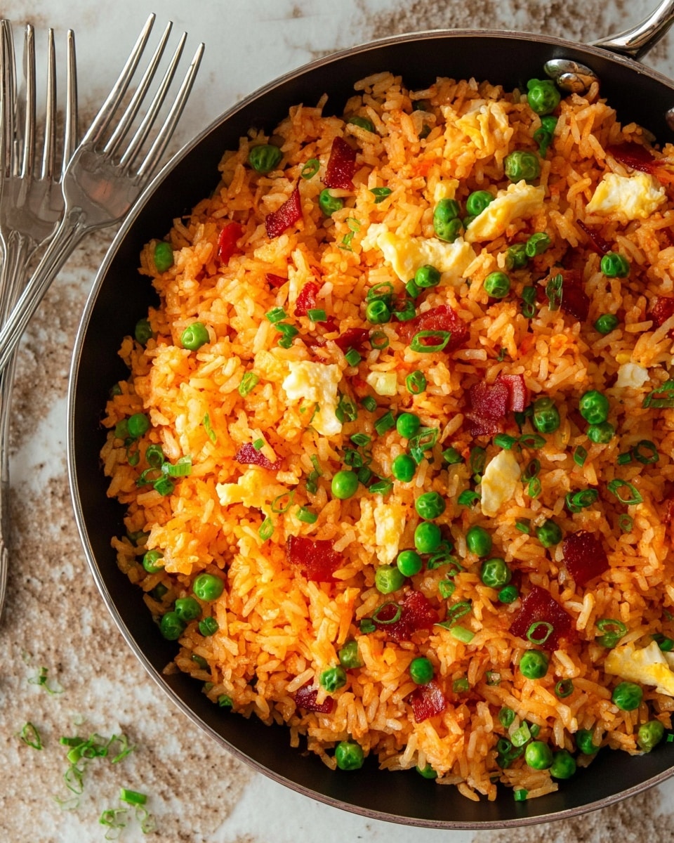 A close-up view of a black pan filled with orange fried rice mixed with green peas, small pieces of red bacon, and white scrambled eggs scattered throughout. The rice is fluffy with some green chive bits sprinkled on top, adding color contrast. The pan is placed on a white marbled textured surface with two silver forks lying nearby. Photo taken with an iphone --ar 4:5 --v 7