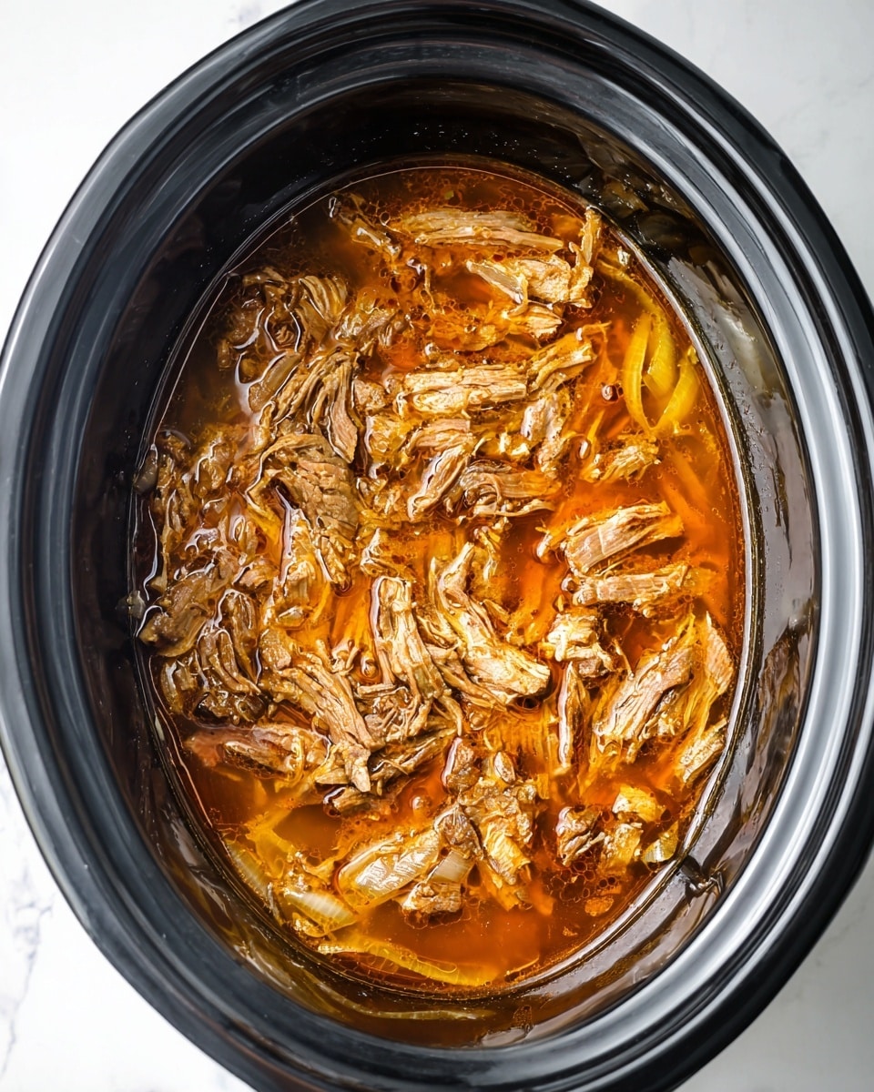 The image shows a slow cooker filled with shredded cooked meat soaked in a rich, orange-brown broth. The meat pieces vary in size and have a tender, fibrous texture. Around the meat, there are translucent, soft onion slices immersed in the broth, adding layers of texture and light yellow color. The slow cooker is dark gray and set on a white marbled surface. Photo taken with an iphone --ar 4:5 --v 7