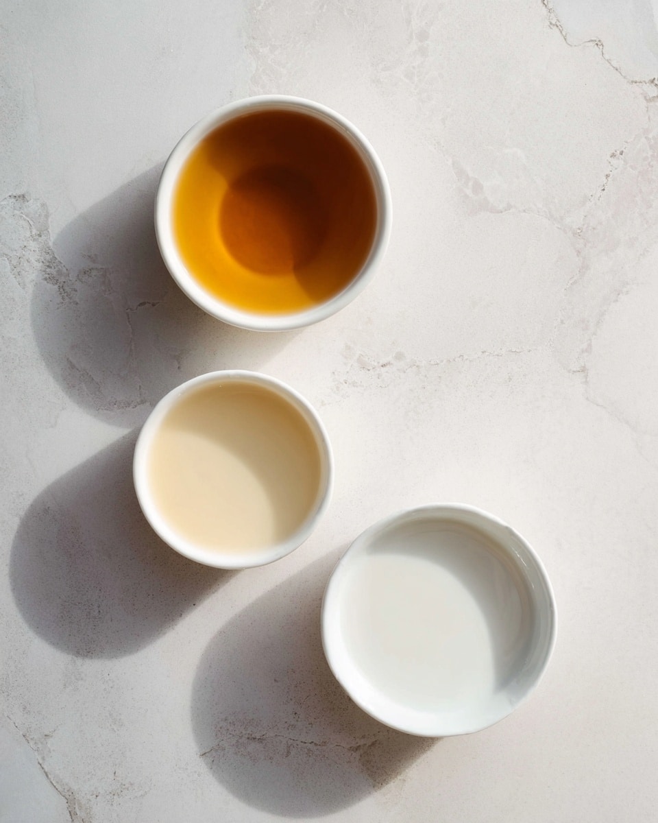 Three white bowls with different liquids sit on a white marbled surface. The top bowl holds a smooth golden-brown liquid. The left bowl, smaller in size, contains a light creamy liquid. The bottom bowl has a white, milk-like liquid. The bowls are spaced evenly, showing textured reflections on the liquid surface. Photo taken with an iphone --ar 4:5 --v 7