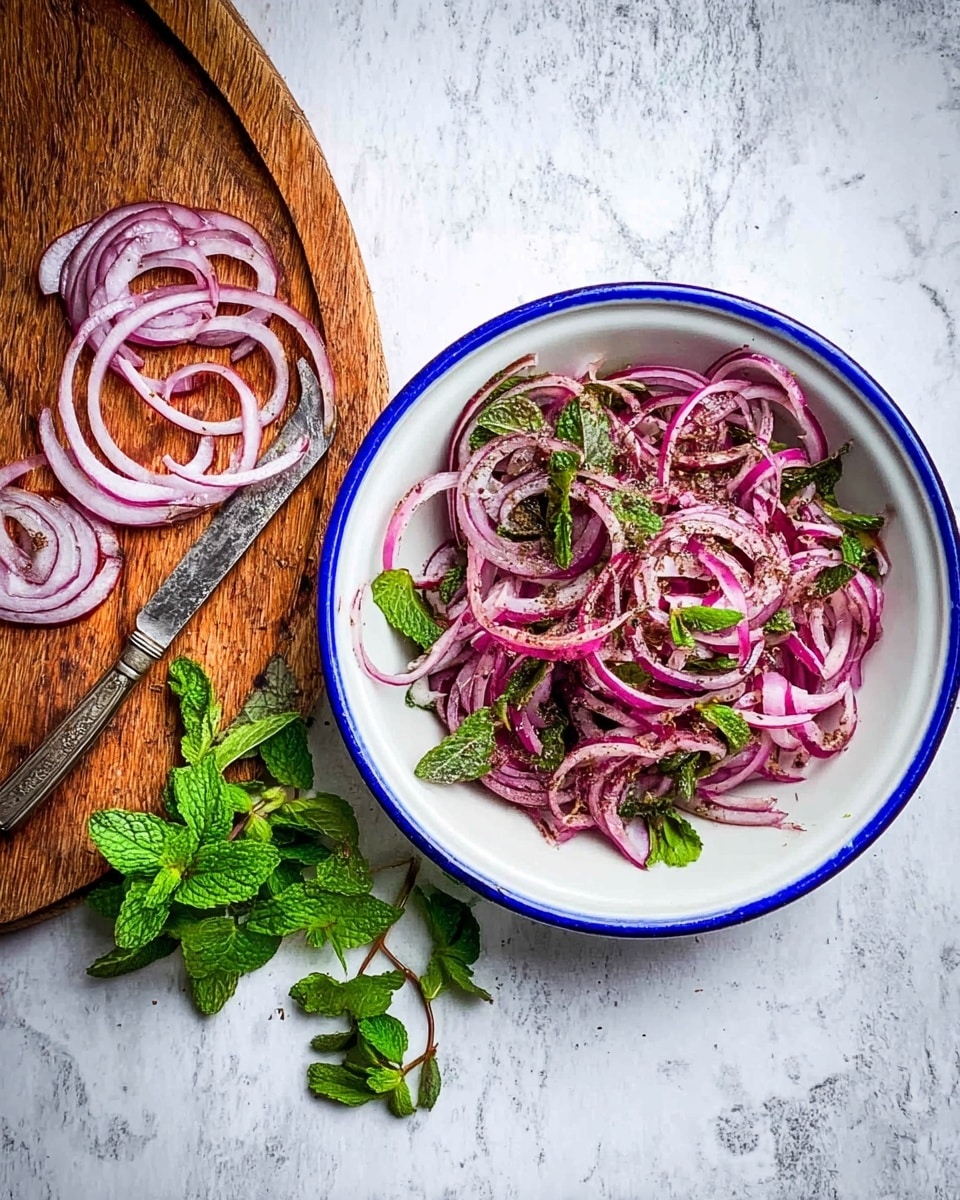 A white bowl with a blue rim sits on a white marbled surface, filled with thin slices of reddish-purple onion mixed with green mint leaves and sprinkled with dark brown spices. To the left, on a round wooden board, there are more raw purple onion slices scattered along with fresh green mint and parsley sprigs, and an old-fashioned silver knife placed diagonally. Photo taken with an iphone --ar 4:5 --v 7