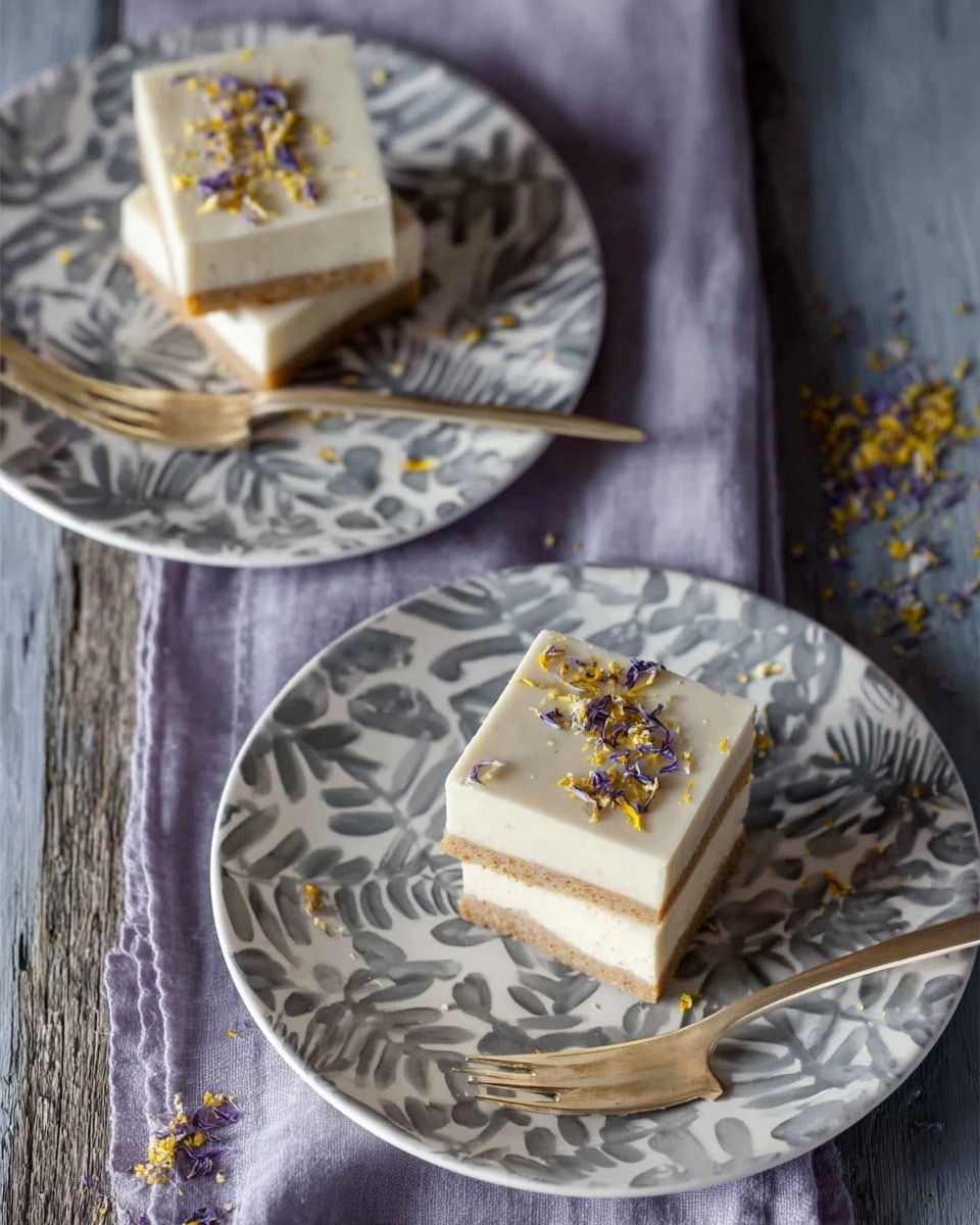 Three square dessert bars stacked on a white plate with a gray leaf pattern. Each bar has two layers: a thick, smooth, creamy white top layer and a thinner, textured brown base layer that looks like a crunchy crust. The top layer is sprinkled with small yellow and purple bits, adding a pop of color. The plate rests on a white marbled surface with scattered crumbs and bits around it. A gold fork lies next to the bars on the plate. In the background, out of focus, is a second white plate with the same pattern holding two more bars and another gold fork. Photo taken with an iphone --ar 4:5 --v 7