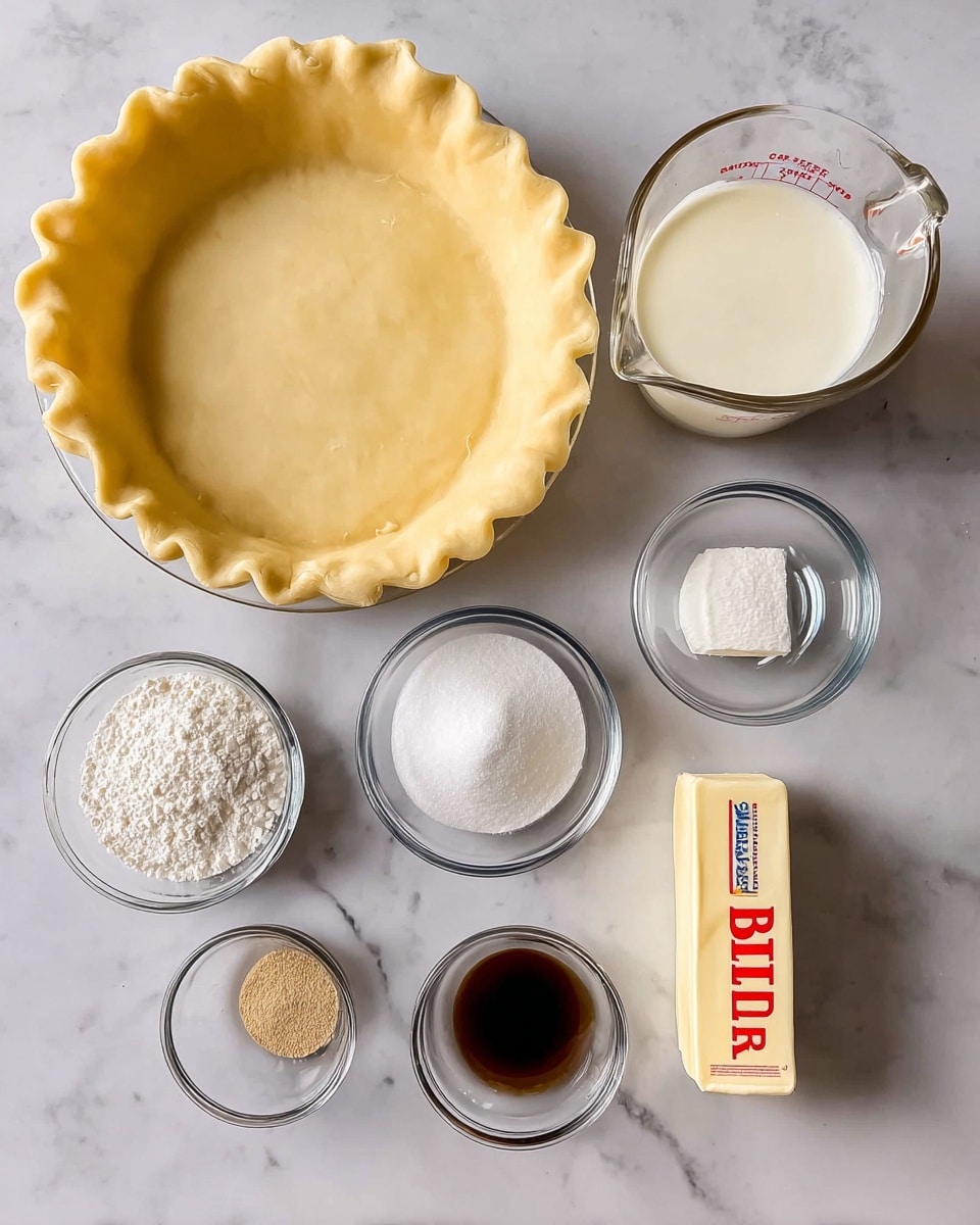 The image shows a top view of several baking ingredients placed on a white marbled surface. Starting from the top left, there is a clear glass pie dish with a smooth, light yellow dough crust pressed evenly inside, with neatly crimped edges around the rim. To the right, there is a clear glass measuring cup with a white creamy liquid filling about half the container. Below, there are five smaller clear glass bowls and a stick of butter arranged neatly: a medium bowl filled with white granulated sugar, a smaller bowl with white powder likely flour or cornstarch, a small bowl with a dark liquid, a tiny bowl containing brown powder, and a stick of butter in a pale yellow color with a wrapper labeled