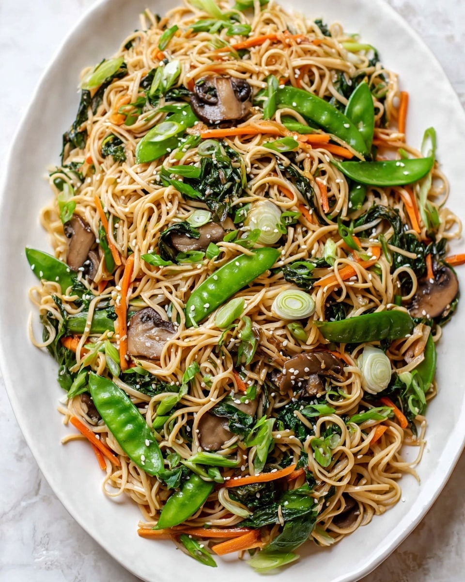 A large white oval plate filled with a mix of light brown cooked noodles layered with green snap peas, chopped green onions, sliced mushrooms, thin orange carrot strips, and wilted leafy greens. The noodles are mixed evenly with all the vegetables, and small white sesame seeds are sprinkled on top for texture and contrast. The plate sits on a white marbled surface. photo taken with an iphone --ar 4:5 --v 7