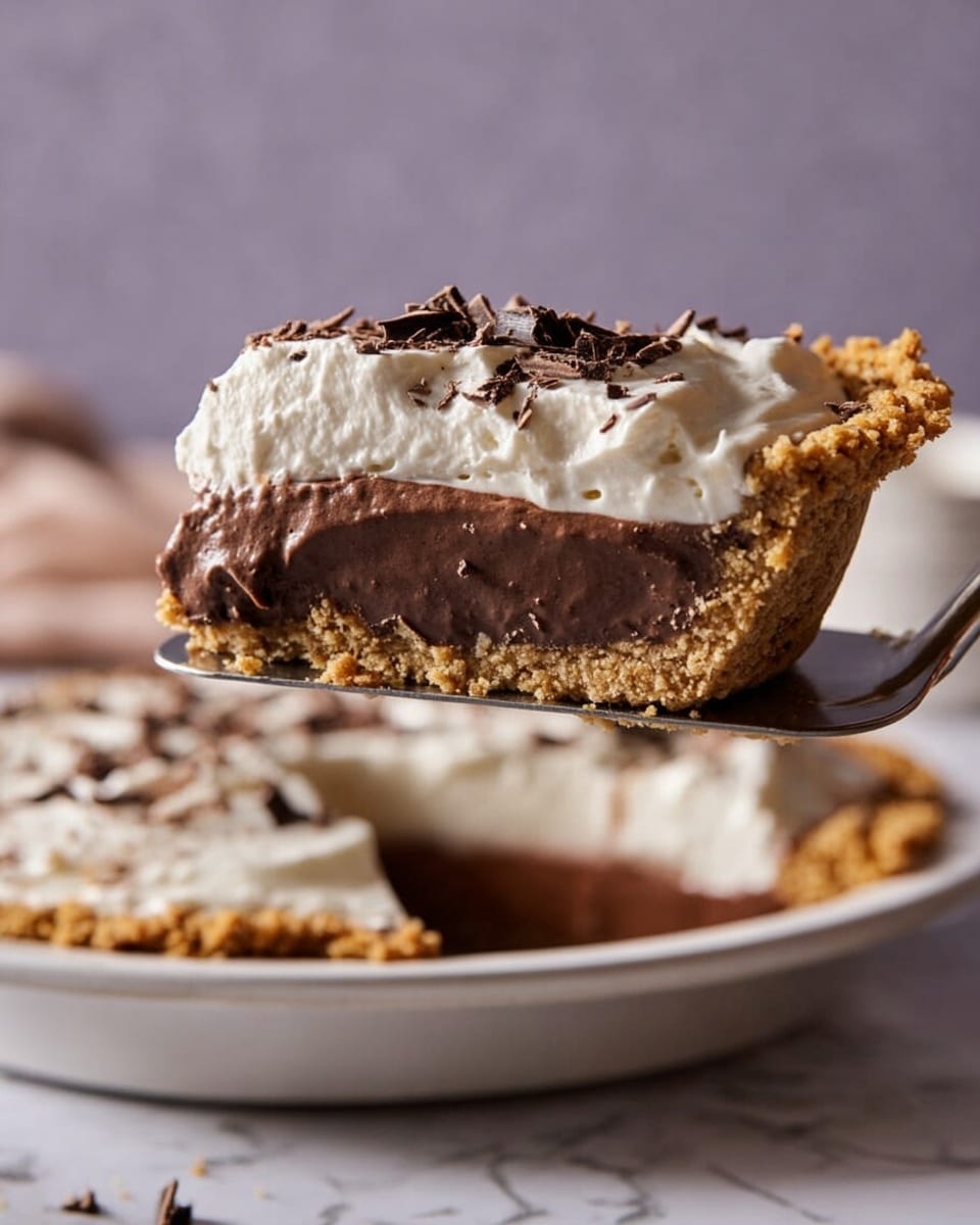 A slice of chocolate pie is held above a whole pie on a white pie plate, showing three layers: a crumbly golden brown crust at the bottom, a smooth and thick dark brown chocolate filling in the middle, and a fluffy white whipped cream layer on top sprinkled with small dark chocolate shavings. The pie is placed on a white marbled surface with a soft, light background. Photo taken with an iphone --ar 4:5 --v 7