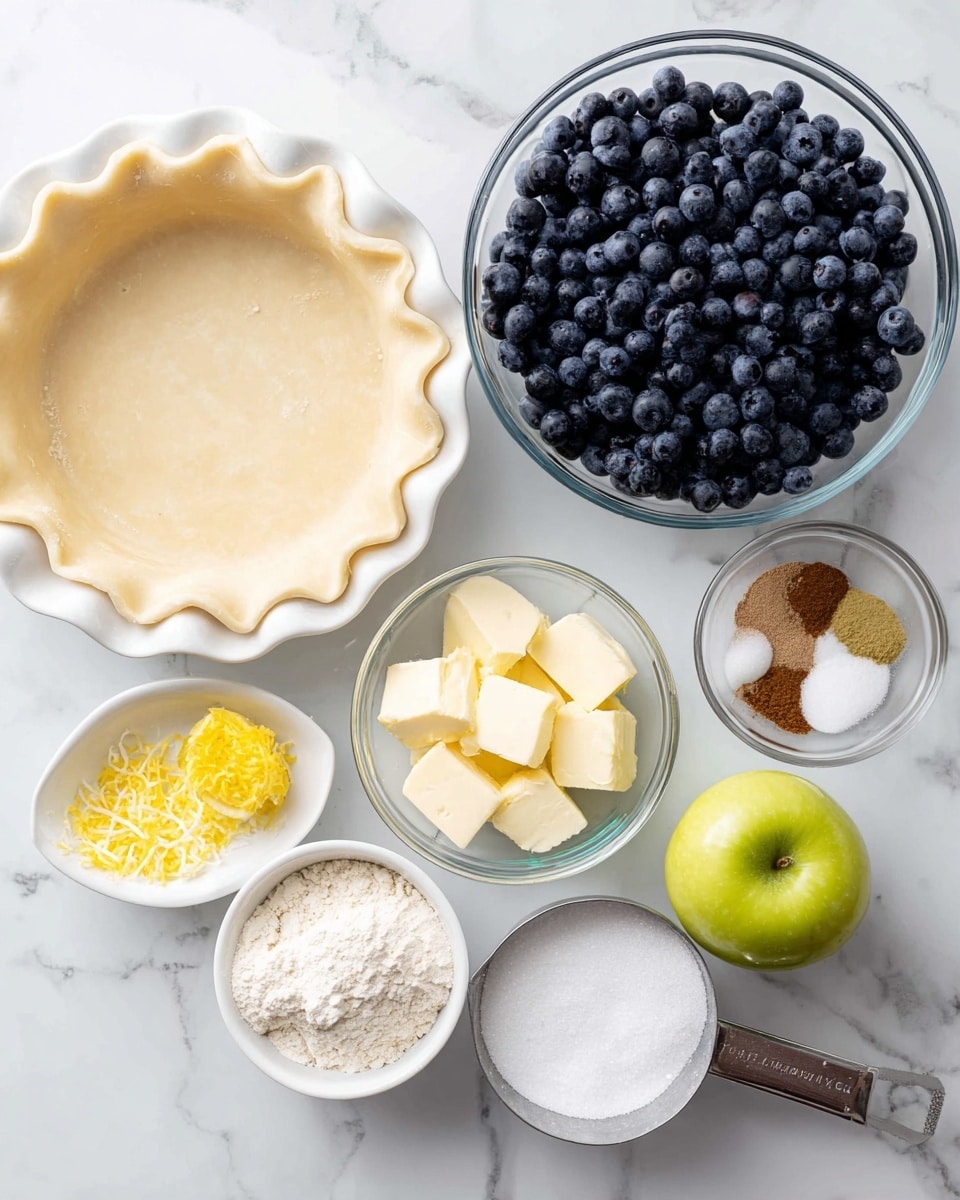 The image shows ingredients for making a blueberry pie arranged neatly on a white marbled surface. There is a white pie dish at the top left with an unbaked light beige crust pressed into it, showing scalloped edges. To the right is a large clear glass bowl filled with fresh, dark blue blueberries. Below the pie dish is a smaller clear glass bowl containing cubed pale yellow butter, granulated white sugar, white flour, and a small pile of brown cinnamon powder. To the bottom left is a small white bowl with bright yellow lemon zest, next to half a lemon showing its juicy pale yellow flesh, and a metal measuring cup filled with white granulated sugar. To the bottom right is a white bowl holding a light green apple. All items are well-lit and arranged clearly for recipe preparation photo taken with an iphone --ar 4:5 --v 7
