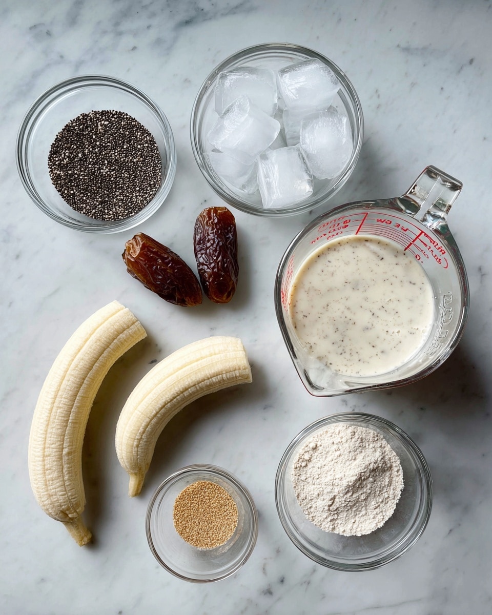 A top view shows a white marbled surface with ingredients placed neatly. On the left side, there is a small clear glass bowl filled with black chia seeds, below it a larger clear glass bowl filled with ice cubes. In the center are two peeled peeled bananas with frost on them, next to two dark brown dates. On the right side, a clear Pyrex measuring cup filled with creamy white liquid is visible. Below it, a small clear glass bowl contains light brown powder, and next to that a medium clear glass bowl is filled with white powder. All items are spaced evenly, showing a clean and simple arrangement. Photo taken with an iphone --ar 4:5 --v 7