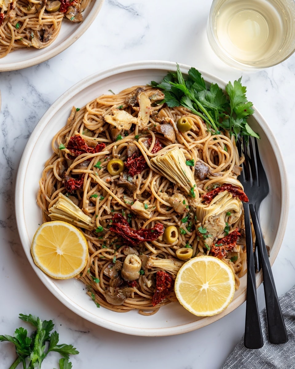 A large white bowl filled with a nest of light brown noodles forms the base layer, mixed with slices of light beige artichoke hearts and dark brown mushrooms scattered on top. Bright red dried tomatoes add a pop of color throughout, and several small green olives are nestled among the noodles. Fresh green cilantro leaves sit on one side, while two lemon wedges with pale yellow skin and juicy interiors rest on the edge of the bowl. Fine yellow lemon zest is sprinkled over the entire dish. Black spoon and fork rest inside the bowl. The bowl sits on a white marbled surface, with a glass of light yellow drink nearby and another similar bowl blurred in the background. Photo taken with an iphone --ar 4:5 --v 7
