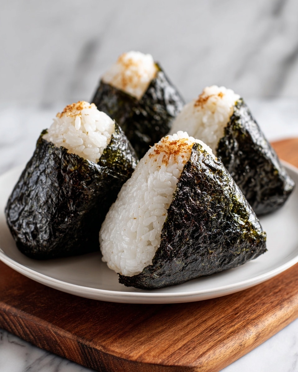 A close-up of a woman's hand holding a triangular-shaped food wrapped tightly in shiny, dark brown to almost black seaweed, showing a slightly bumpy texture on the surface. The background is a soft white marbled texture, and the focus is on the wrapped food, which appears compact and slightly glossy. photo taken with an iphone --ar 4:5 --v 7