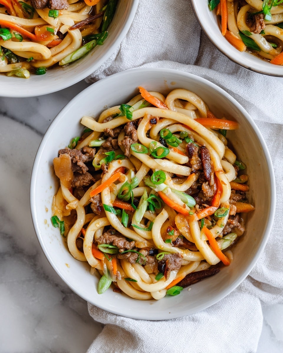 This image shows two dishes of stir-fried udon noodles with beef and vegetables. The main dish in the center is served in a white bowl with thick, light brown udon noodles twisted into a pile. Mixed within the noodles are thin strips of cooked beef, light brown in color, along with small pieces of orange carrot. The dish is topped with fresh green sliced scallions scattered evenly. In the top right corner, another white bowl contains the same dish, partially visible. Both bowls rest on a smooth white marbled surface, with a soft white cloth partially under the bowl in the front. The lighting is bright and natural, highlighting the textures and colors of the food. photo taken with an iphone --ar 4:5 --v 7