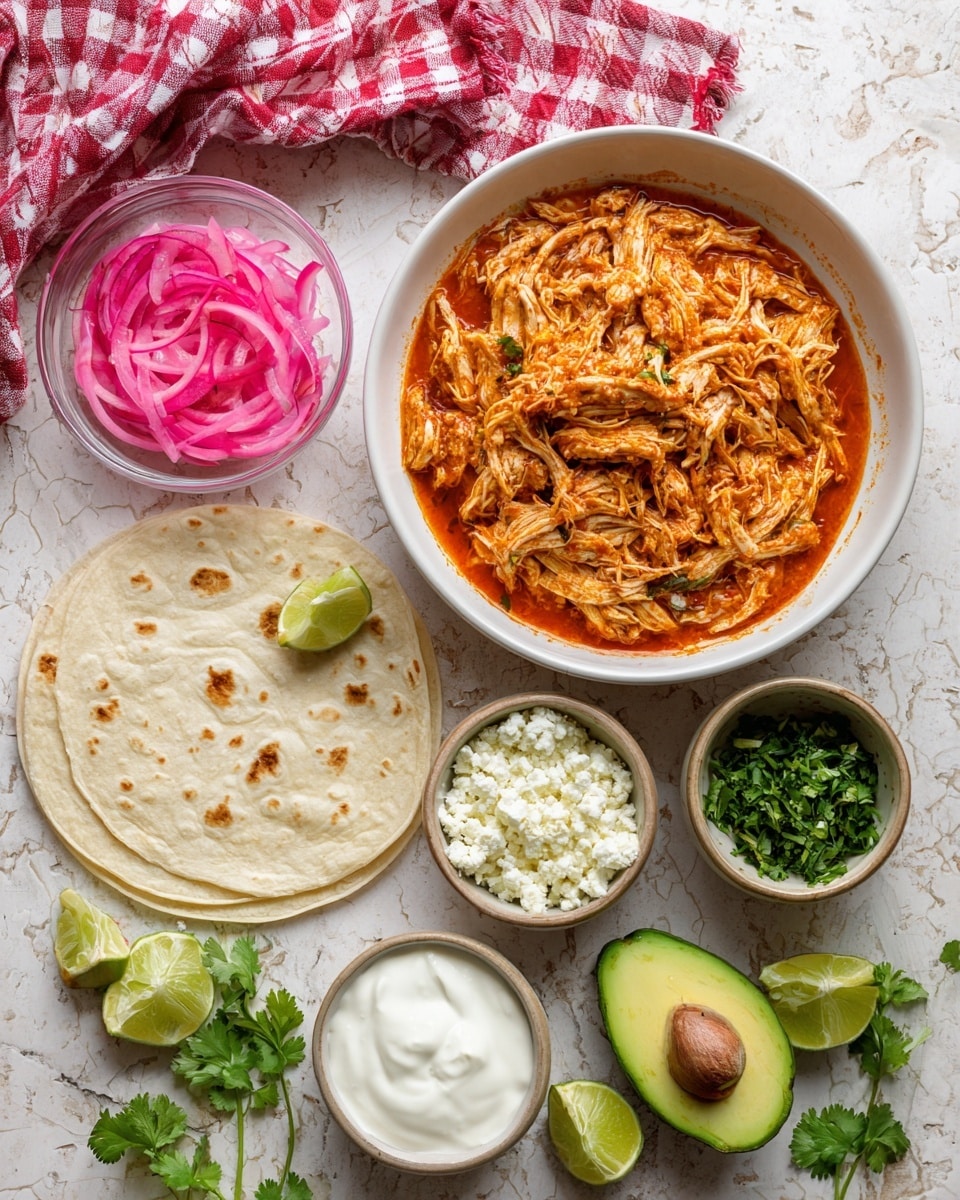 A flat white tortilla lies flat on the right side over a white marbled textured surface. To the left of the tortilla is a white bowl filled with shredded chicken mixed with a rich, reddish-orange sauce. Above the bowl is a whole avocado cut in half, showing its green creamy inside and the brown seed in one half while the other half is empty. Below the bowl are several small white bowls lined vertically: the top one contains crumbly white cheese, the middle one has chopped green herbs, the next bowl holds bright green lime wedges, and the bottom bowl is filled with white sour cream. To the top left, there is a small clear bowl with thin, bright pink pickled onions, and a red and white checkered cloth behind it. Sprigs of fresh green herbs are scattered around the table. Photo taken with an iphone --ar 4:5 --v 7