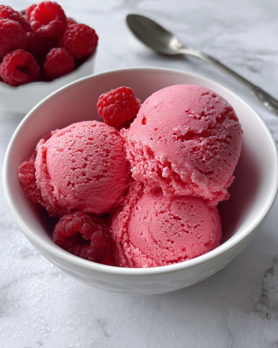 A round white bowl filled with three scoops of bright pink ice cream, with texture showing some small chunks. The ice cream fills the bowl halfway, with some areas scraped away revealing the white inside of the bowl. The bowl is placed on a white marbled surface, with a white cloth visible on the right side and a small white bowl with fresh raspberries partially visible on the bottom left. Photo taken with an iphone --ar 4:5 --v 7