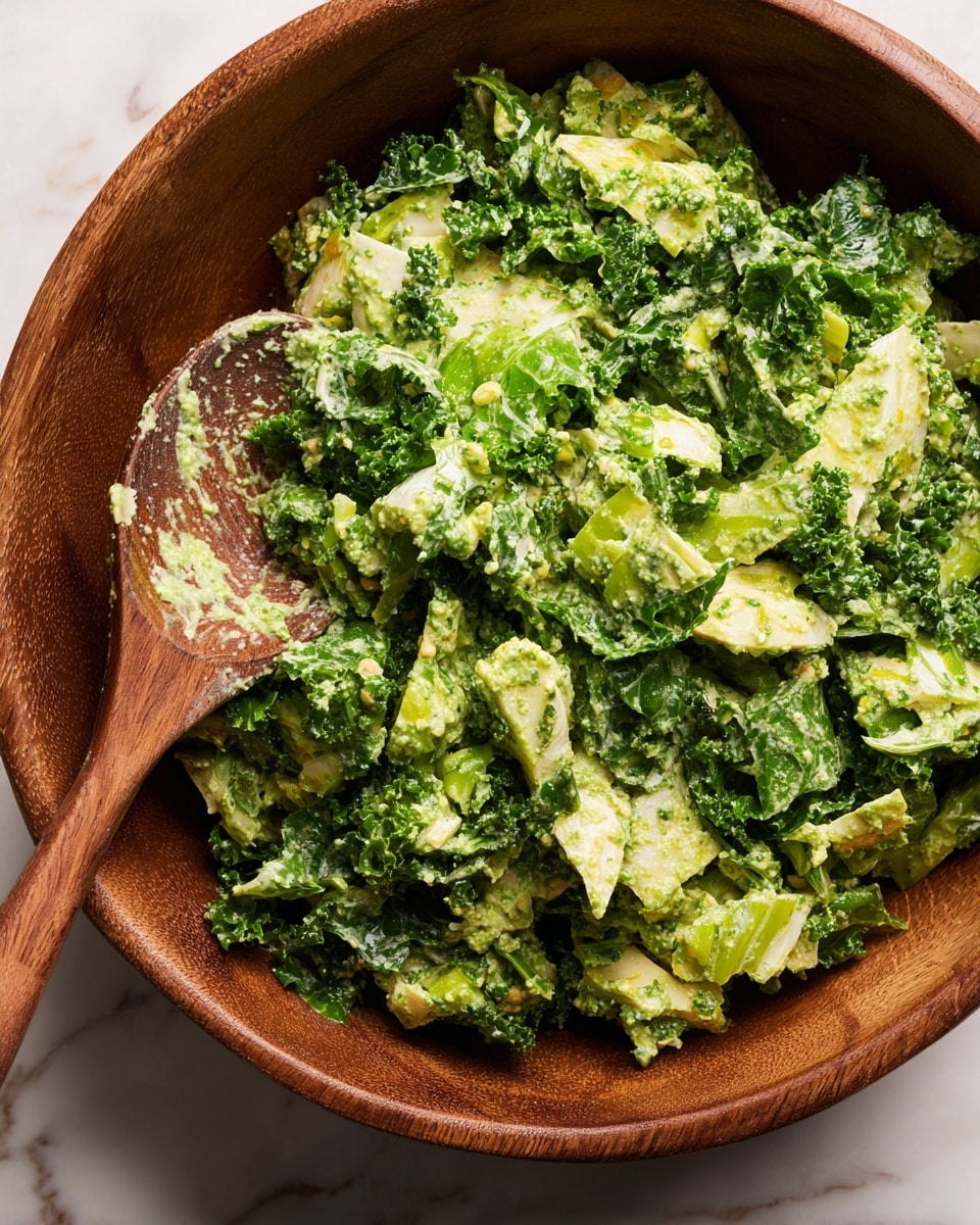 A wooden bowl filled with a green salad made of chopped pale green cabbage and darker green cucumber slices, all coated in a thick, chunky green dressing that looks creamy and herb-filled. The salad has uneven, rough pieces of vegetables mixed well with the sauce, creating a fresh and textured look. A wooden spoon with some dressing on it rests partly in the bowl. The bowl sits on a white marbled surface. photo taken with an iphone --ar 4:5 --v 7