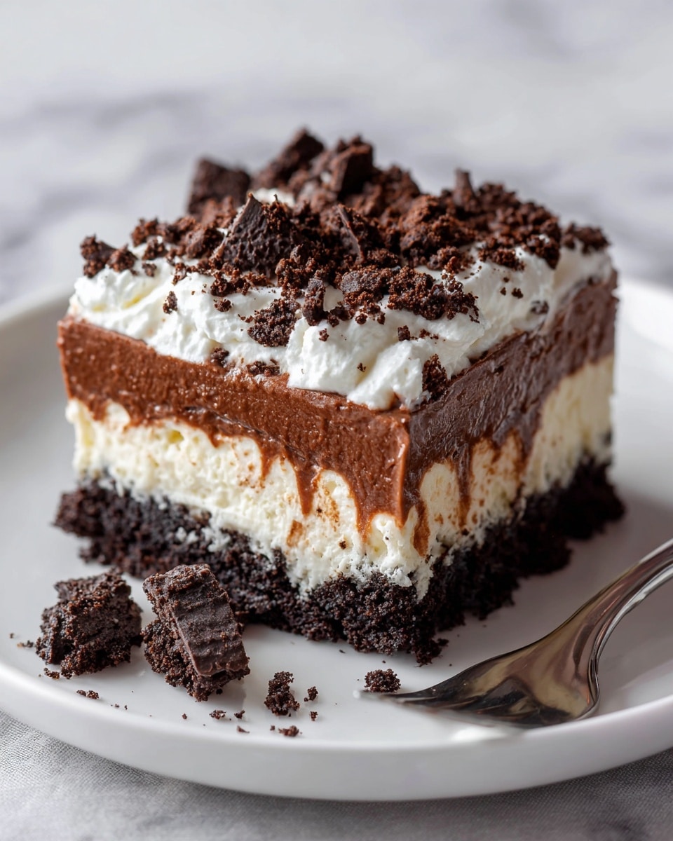 The image shows a square slice of layered dessert on a white plate with a white marbled surface in the background. The dessert has four visible layers: a bottom dark chocolate crumb crust, a lighter creamy beige layer above it, then a thick milk chocolate pudding layer, and a fluffy white whipped cream layer on top. The top layer is sprinkled with crushed dark chocolate cookie pieces, some of which are scattered next to the slice on the plate. A fork is partially visible behind the dessert. The photo taken with an iphone --ar 4:5 --v 7