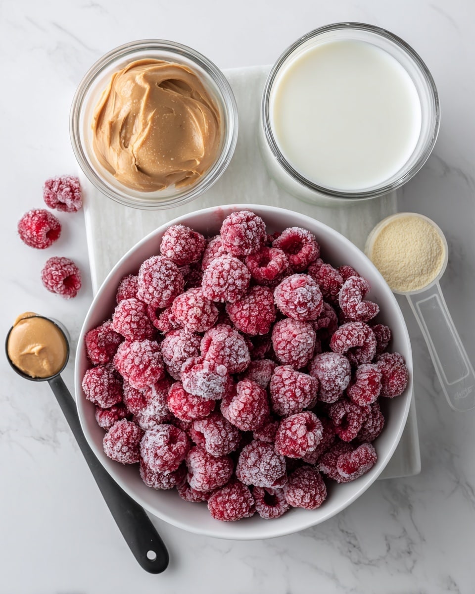 A white bowl filled with a layer of frozen red raspberries covered in frost sits on a white marbled surface, surrounded by a black measuring spoon with a scoop of light brown peanut butter on the left, a clear measuring cup filled with white milk on the top right, and a transparent scoop filled with pale yellow powder on the bottom right, all placed on a white marbled textured board. photo taken with an iphone --ar 4:5 --v 7