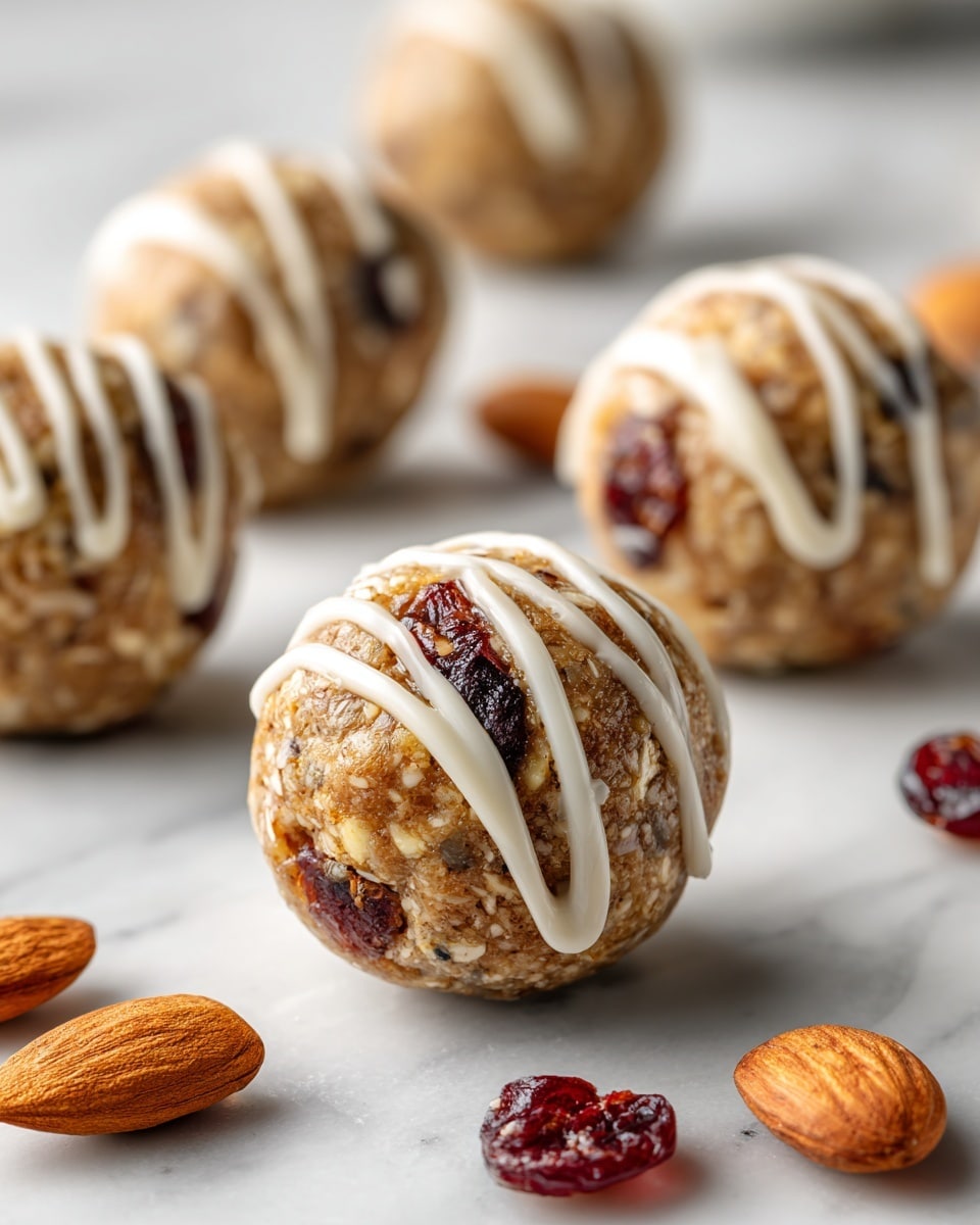 The image shows several round, textured energy balls that are light brown with small bits of darker brown and cream colors inside, giving a nutty appearance. Each ball is drizzled with thin white lines of icing on top, creating a web-like pattern. The energy balls are placed on a white marbled surface, and the focus is on the closest ball with others softly blurred in the background. photo taken with an iphone --ar 4:5 --v 7
