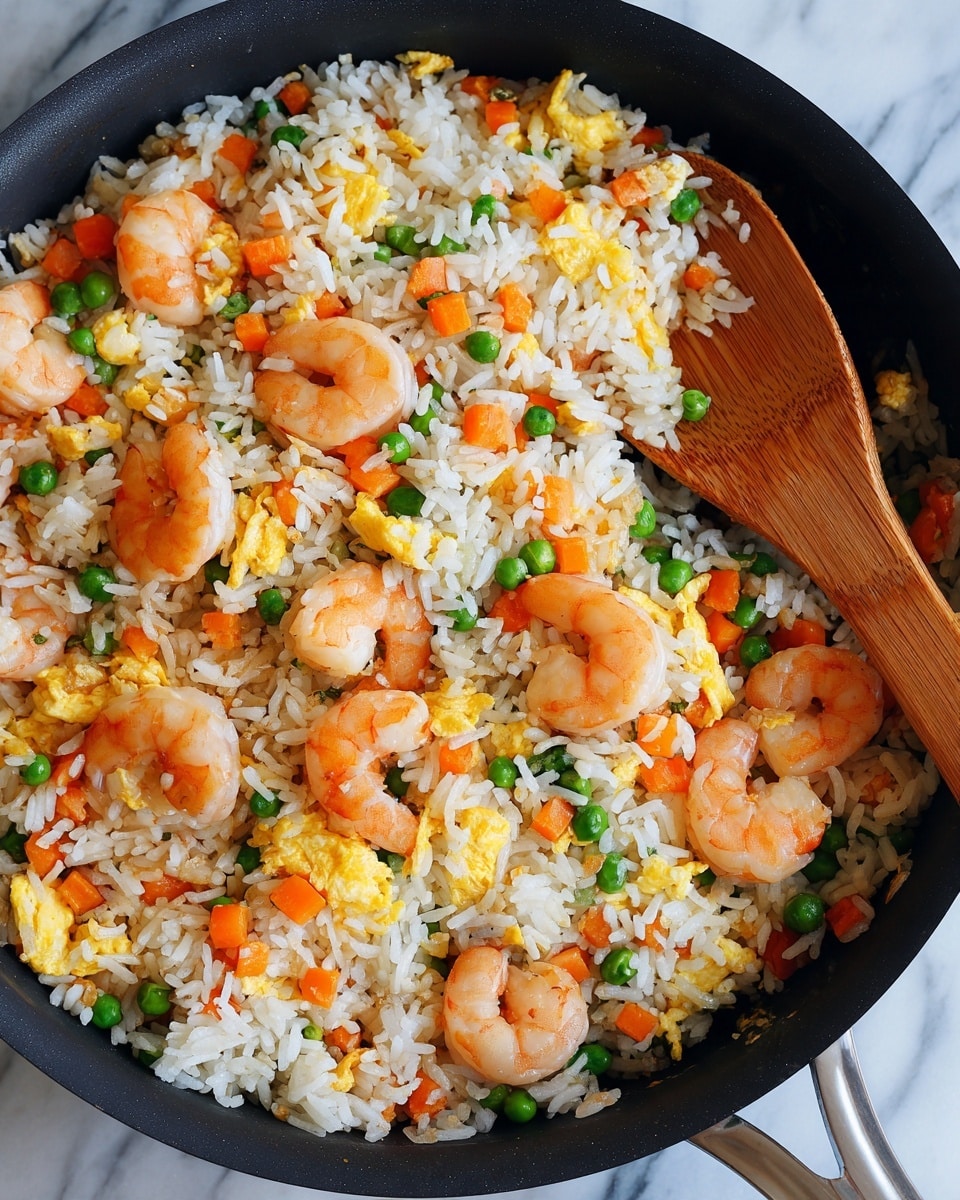 A close-up view of a pan filled with shrimp fried rice seen from above, showing at least four layers: the first layer is white rice with a soft and fluffy texture spread evenly across the pan; scattered throughout are bright orange cooked shrimp, some slightly curled; the third layer has small diced carrots and green peas mixed evenly in, adding pops of orange and green; the fourth layer includes small scrambled egg pieces in yellow, spread over all the other ingredients; a wooden spoon is resting on the right side of the pan, partially lifting some of the fried rice. The pan is placed on a white marbled surface. photo taken with an iphone --ar 4:5 --v 7